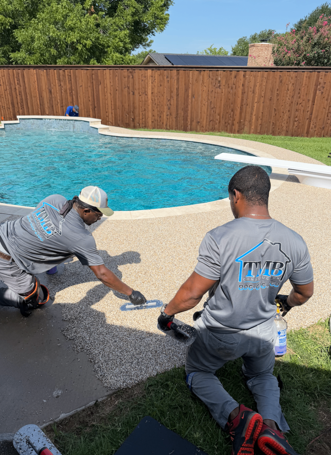 TMB Construction crew hand-troweling rubber surfacing around a pool deck