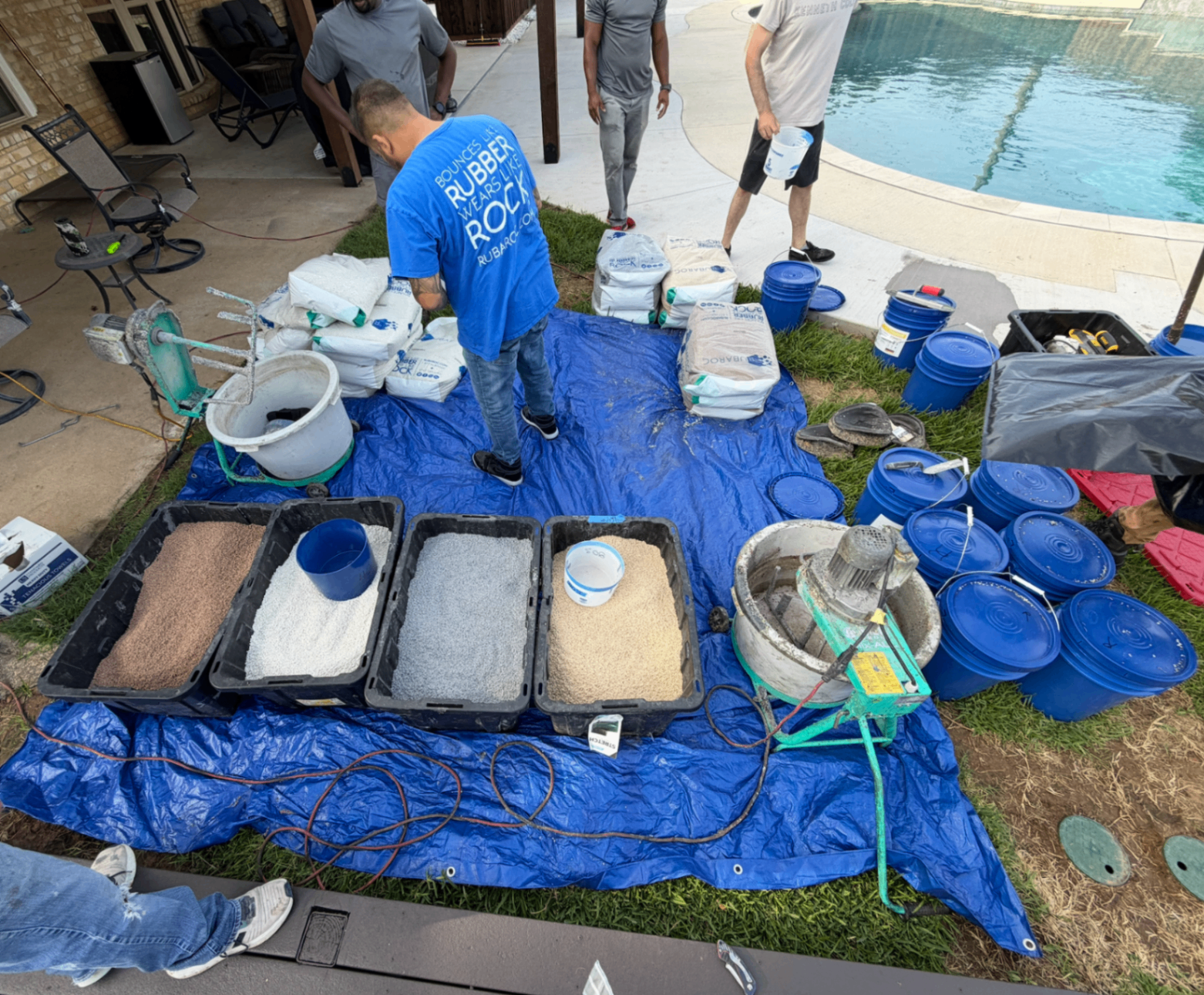 Rubber surfacing materials and crew setup before installation around a pool