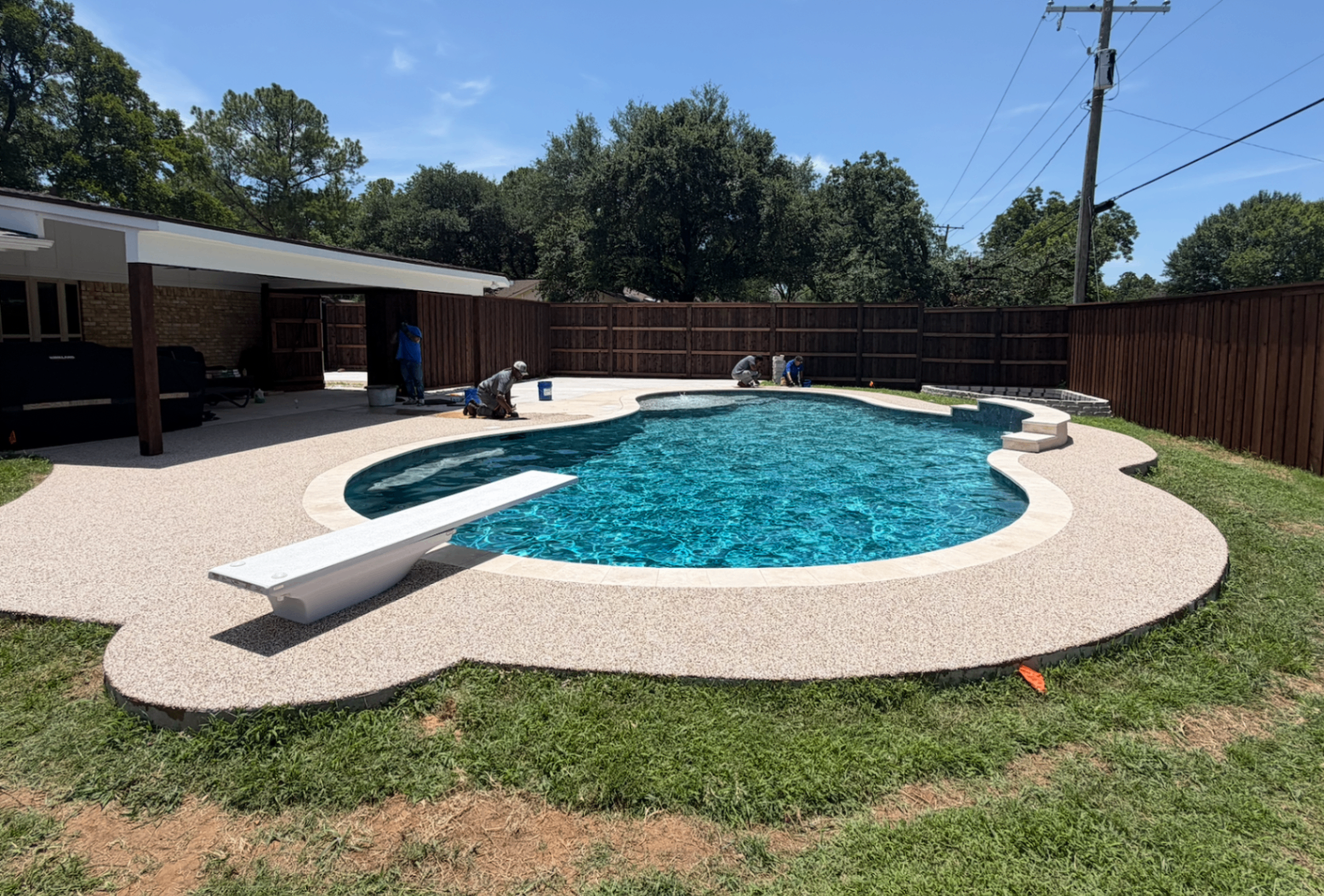 TMB Construction crew applying rubber surfacing at a pool deck project in progress